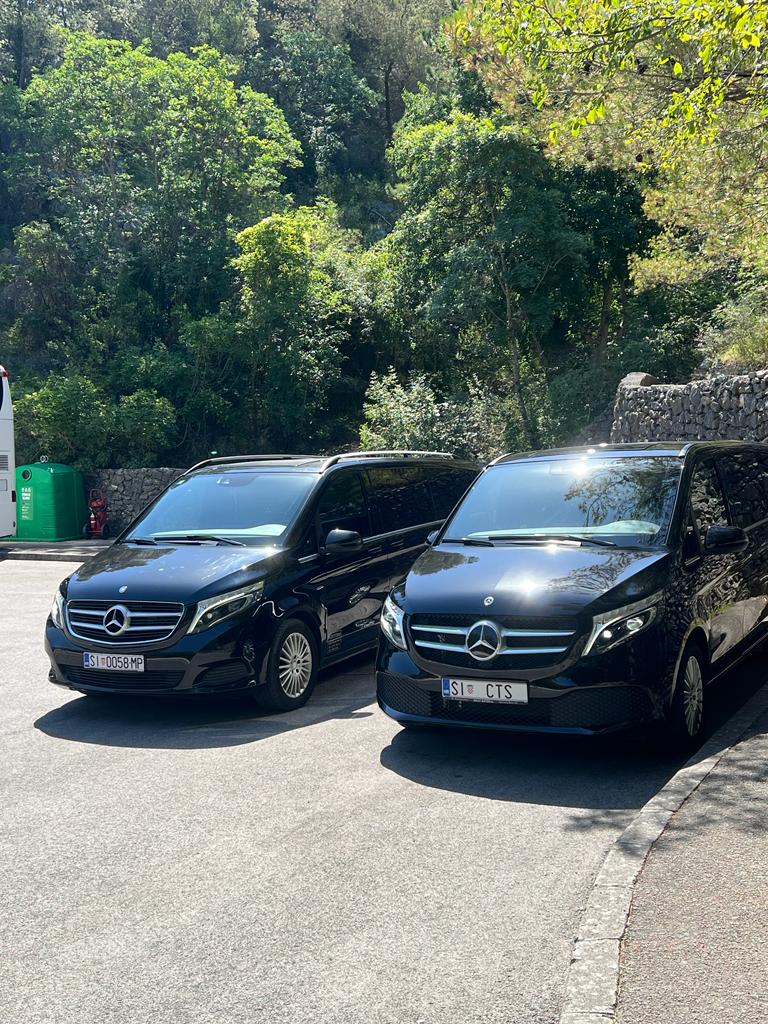 Two black Mercedes V-Class Cipollina minivans parked side by side at a Dalmatian rest stop, ready for airport transfers